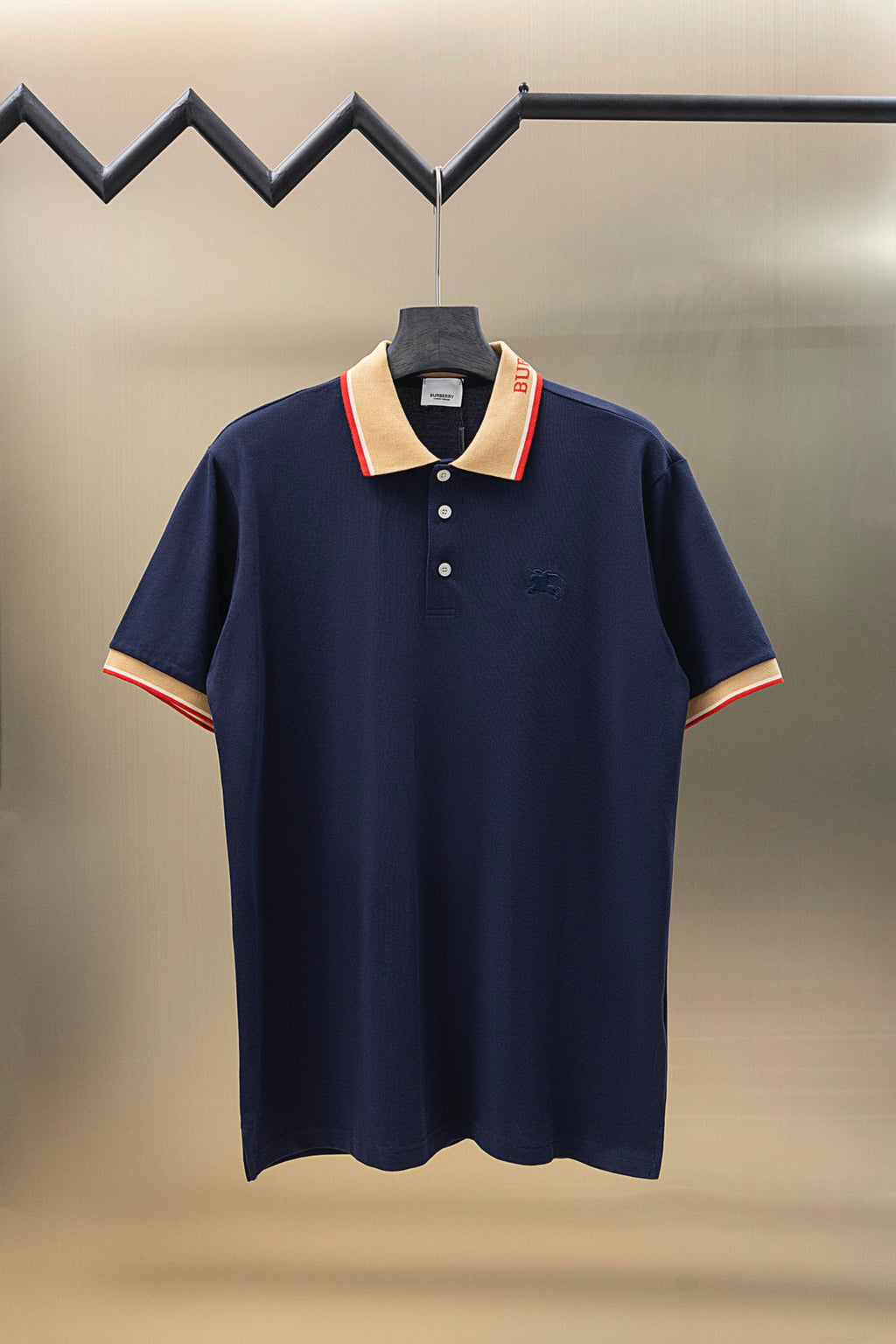 Navy polo shirt with beige and red striped collar and short sleeves, button placket