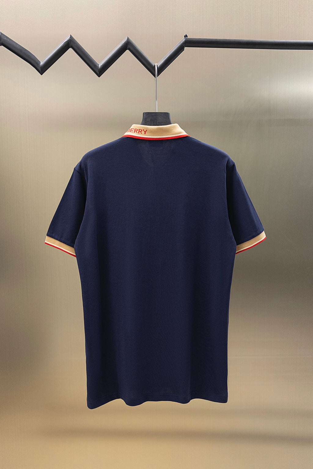 Navy polo shirt, back view on hanger, short sleeves with beige and red trim