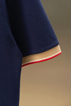 Navy polo shirt sleeve hem with beige band and red stripe