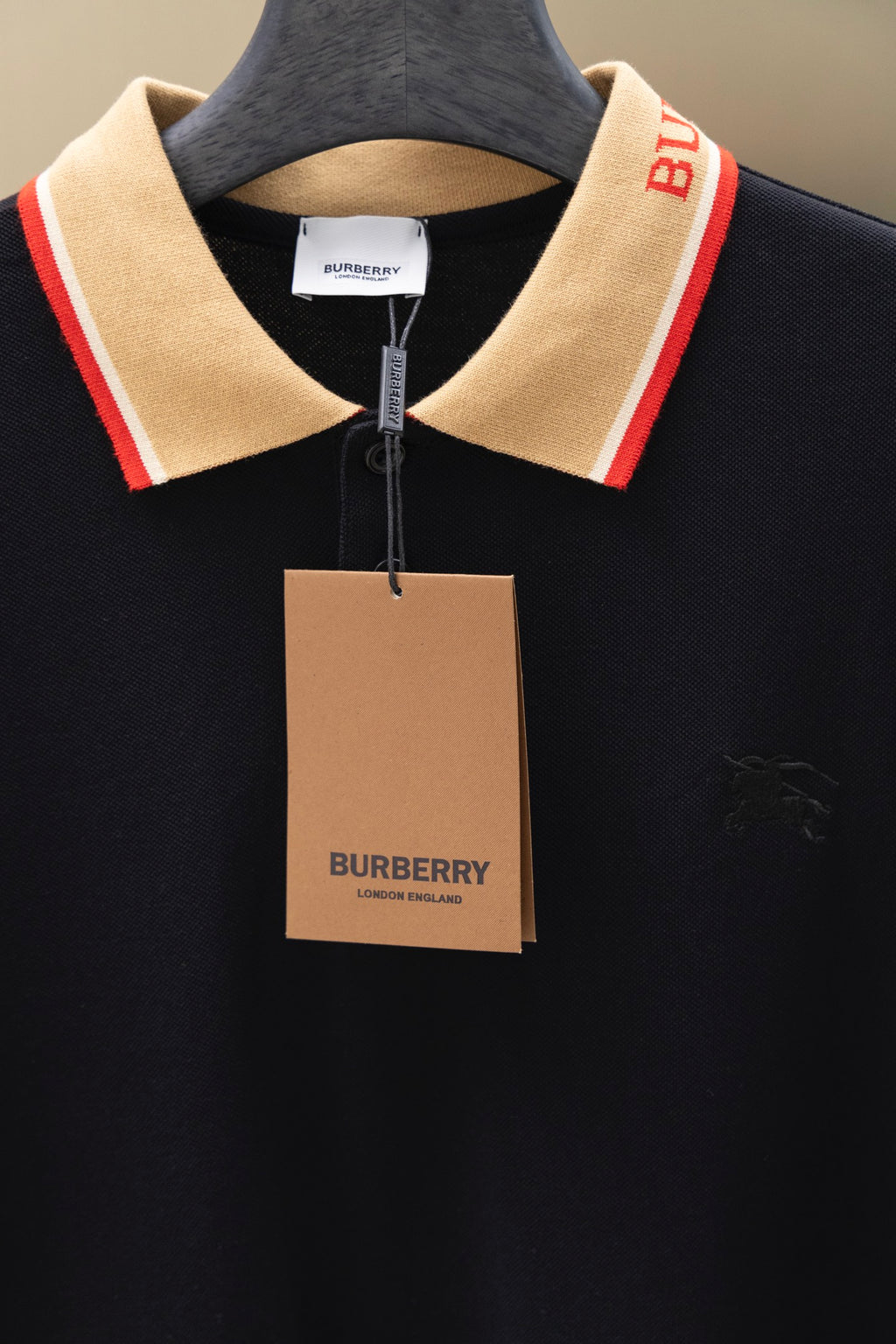 Burberry polo shirt with beige collar, red trim, and hanging price tag