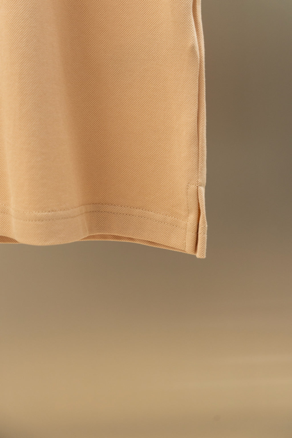 Light beige polo shirt hem detail with clean straight bottom edge