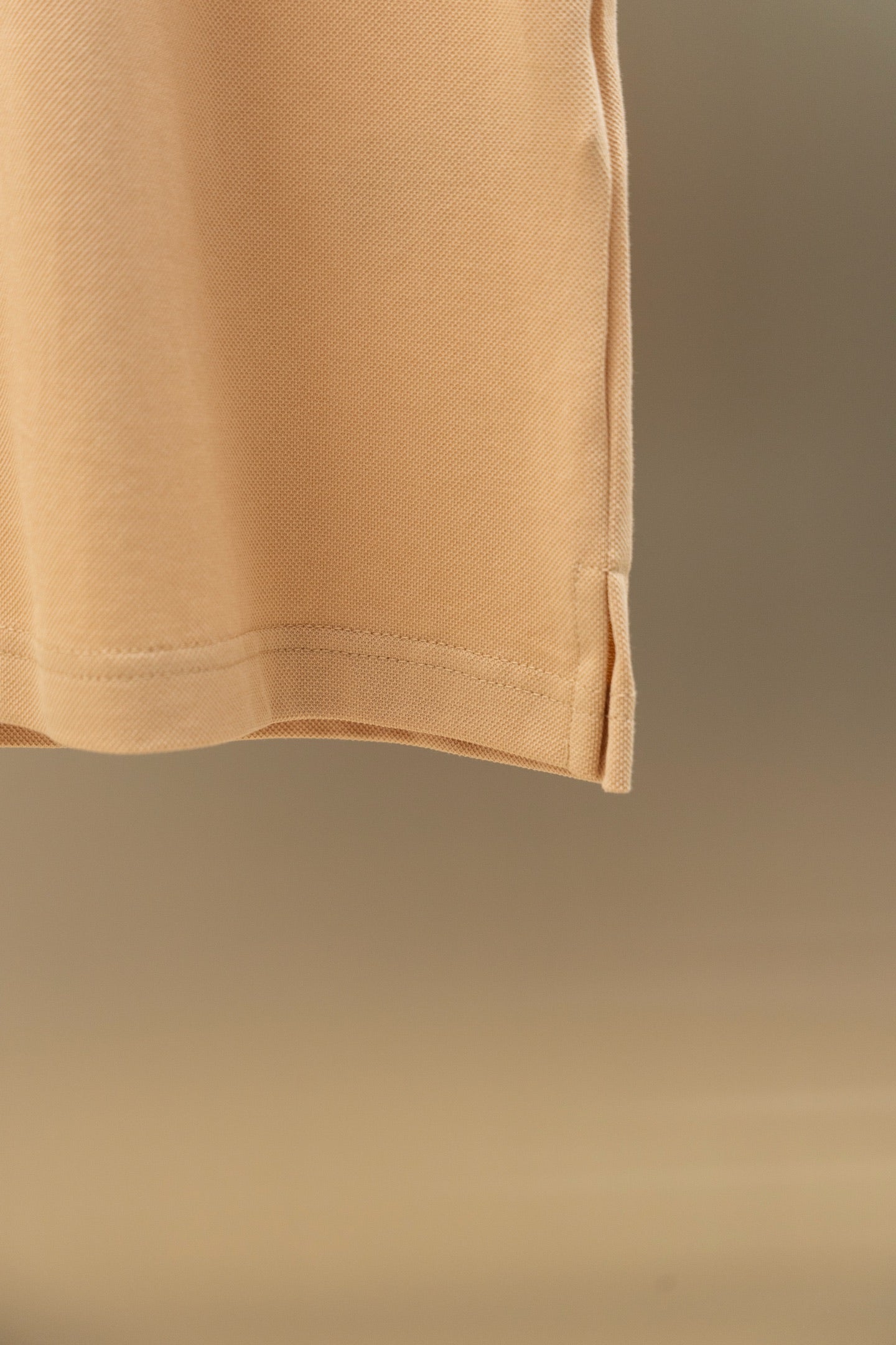 Light beige polo shirt hem detail with clean straight bottom edge