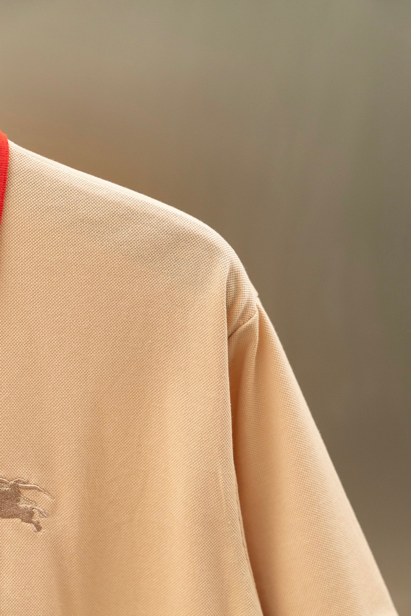 Light beige polo shirt side close-up with small chest logo detail