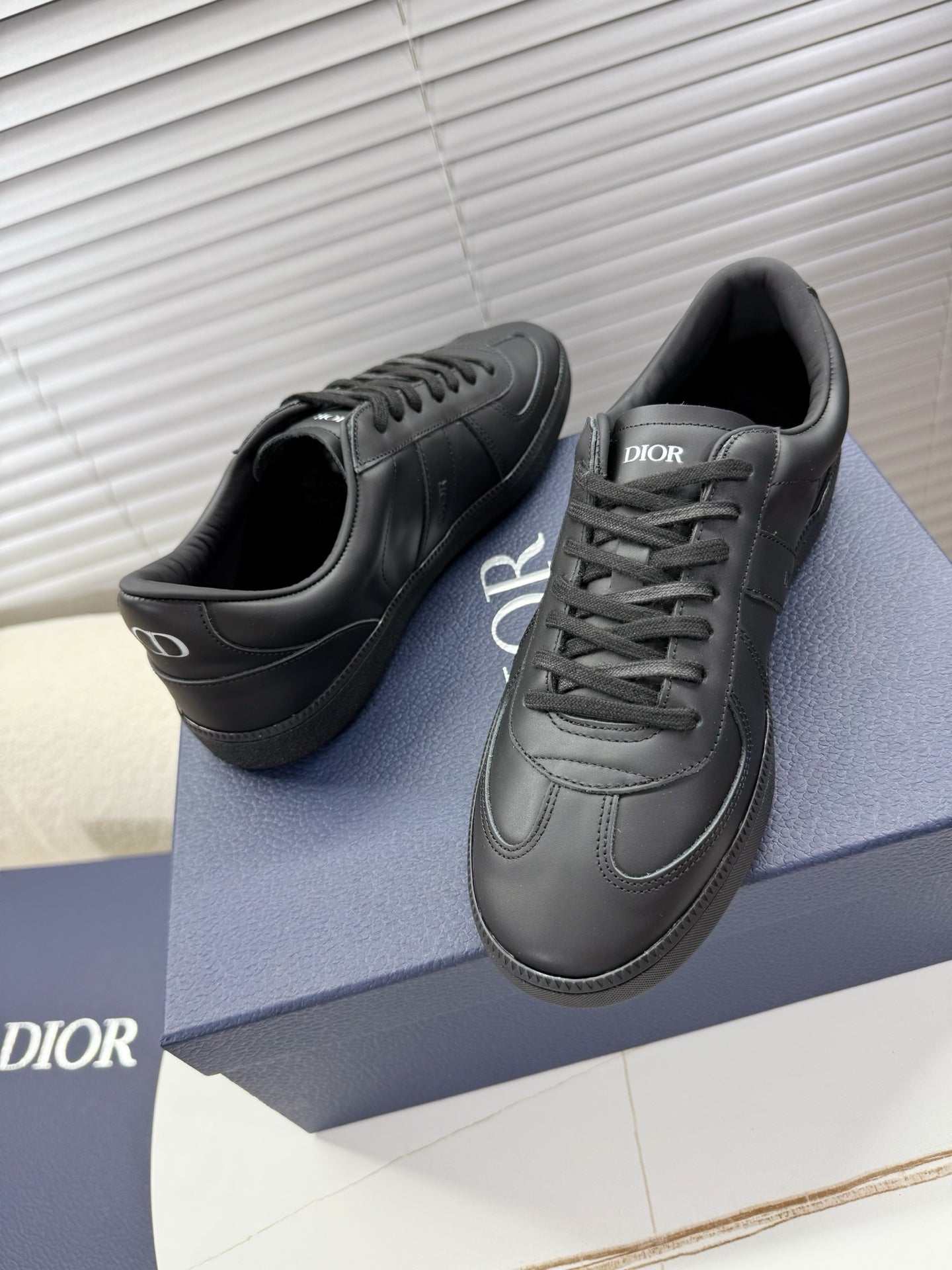 Dior dark leather sneakers with lace-up and side logo on curved toe.