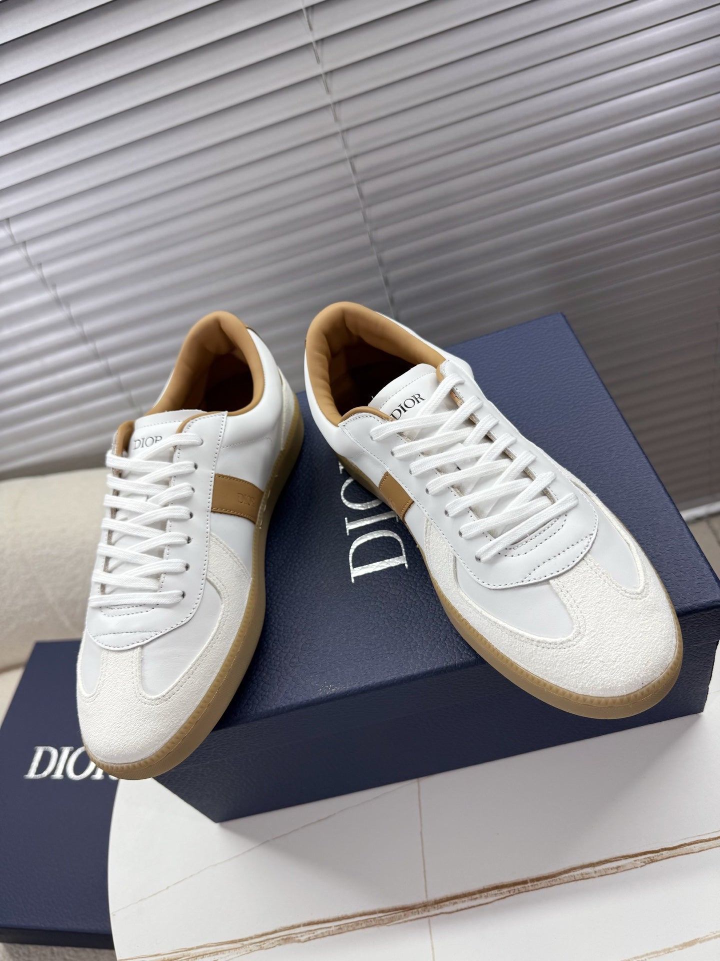 White lace-up sneakers with tan side stripe and gum-style rubber sole
