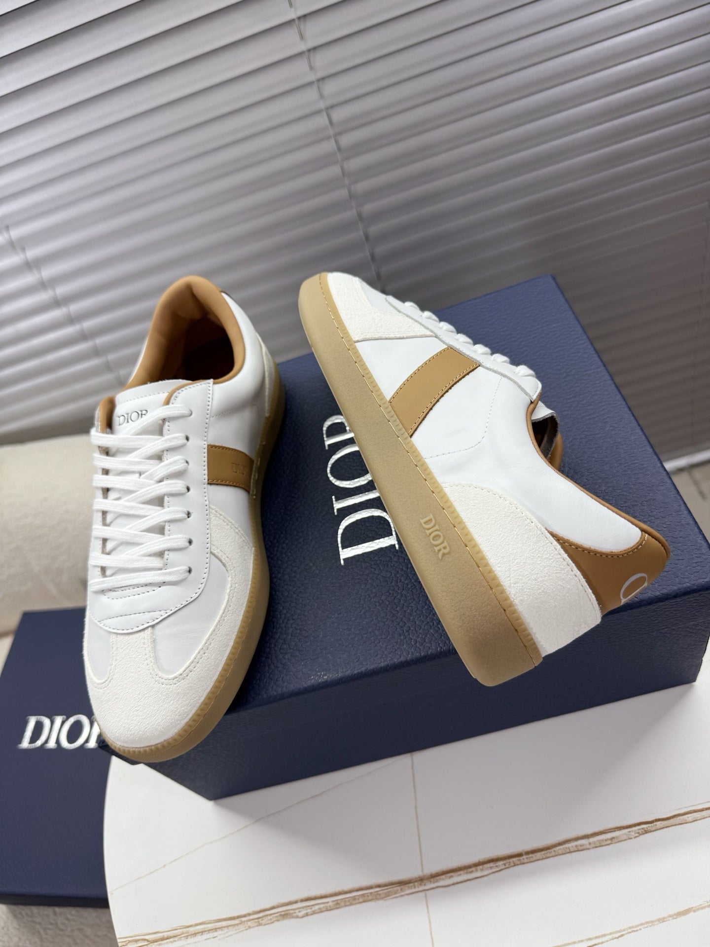 White Dior sneakers with tan side panels and lace-up front
