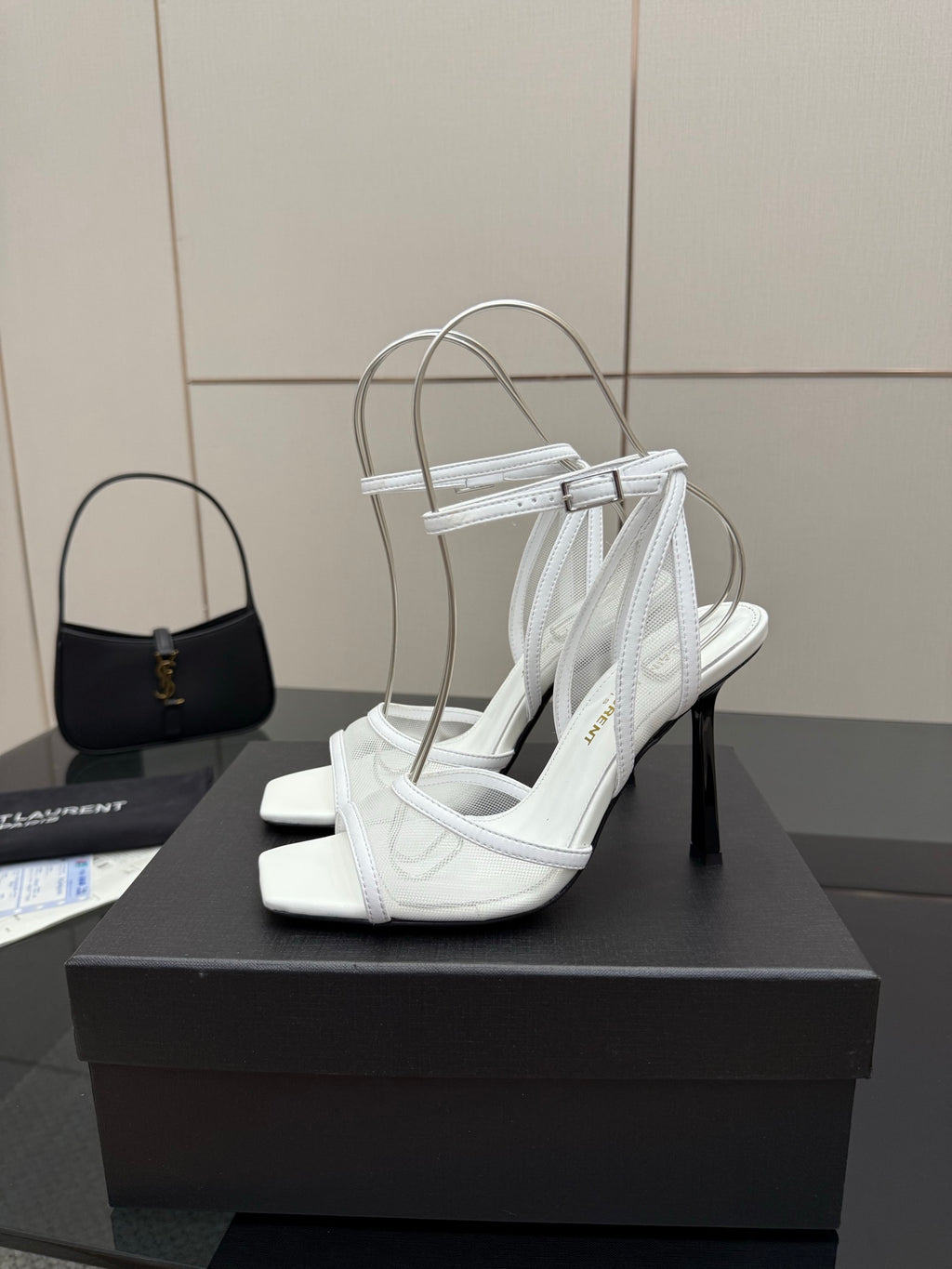 White women’s heeled sandal on display stand, open toe with ankle strap and slim heel