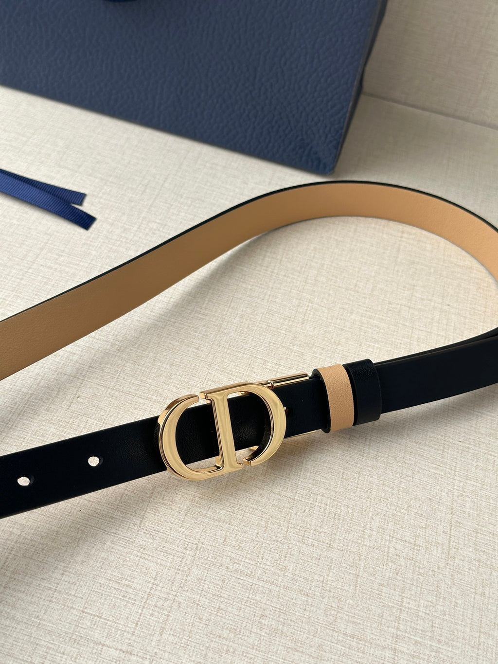Narrow leather belt with navy face, tan stripe, and gold-tone CD buckle