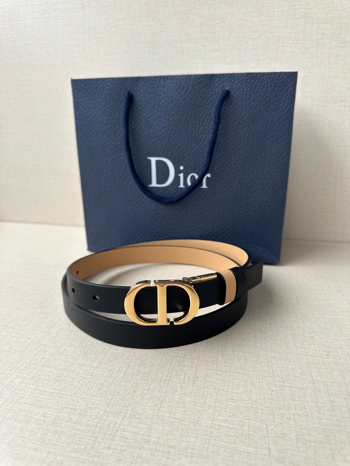 Leather belt with navy strap, tan stripe, and gold-tone CD buckle