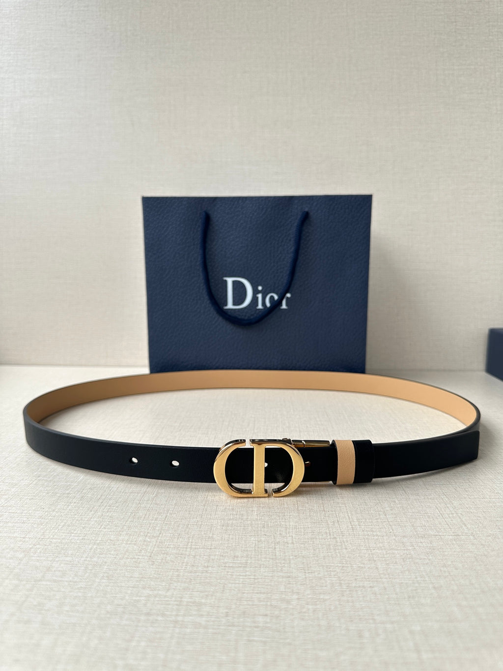 Leather belt with navy strap, tan stripe, and gold-tone CD buckle