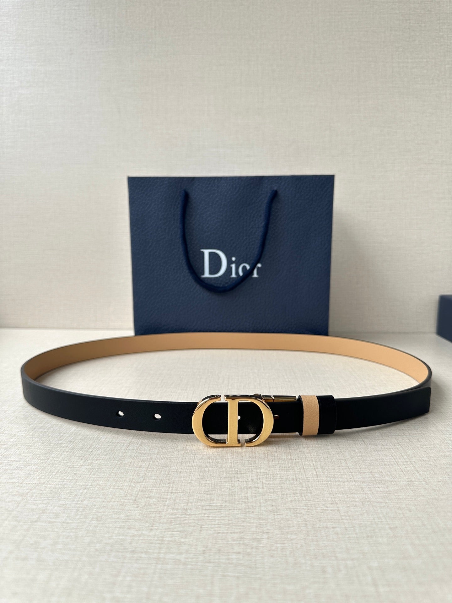 Leather belt with navy strap, tan stripe, and gold-tone CD buckle