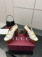 Pair of white open-back mules with gold buckle hardware and chunky brown block heels