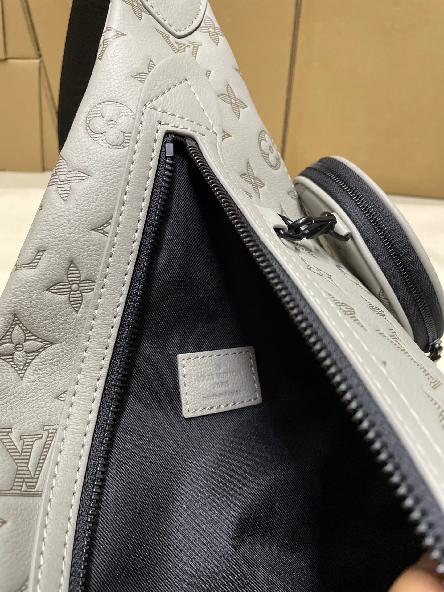 Men's Louis Vuitton monogram sling bag open interior with black lining and zipper