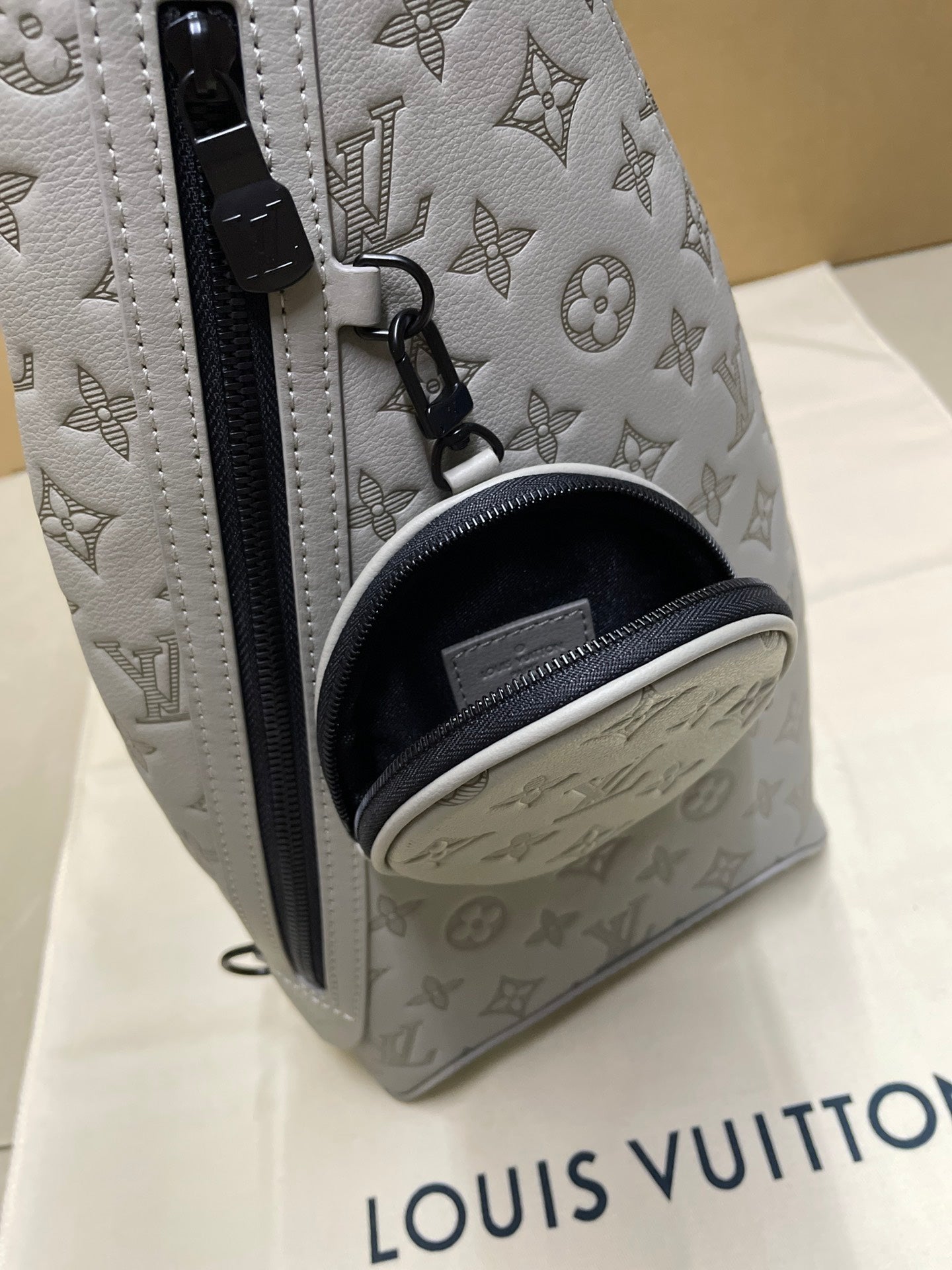 Men's Louis Vuitton monogram sling bag corner view, light gray/white with black lining