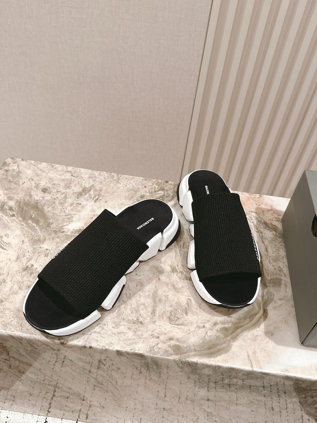 Black knit slide sandals with chunky white sole and Balenciaga logo strap.