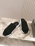 Black knit slide sandals with chunky white sole and Balenciaga logo strap.