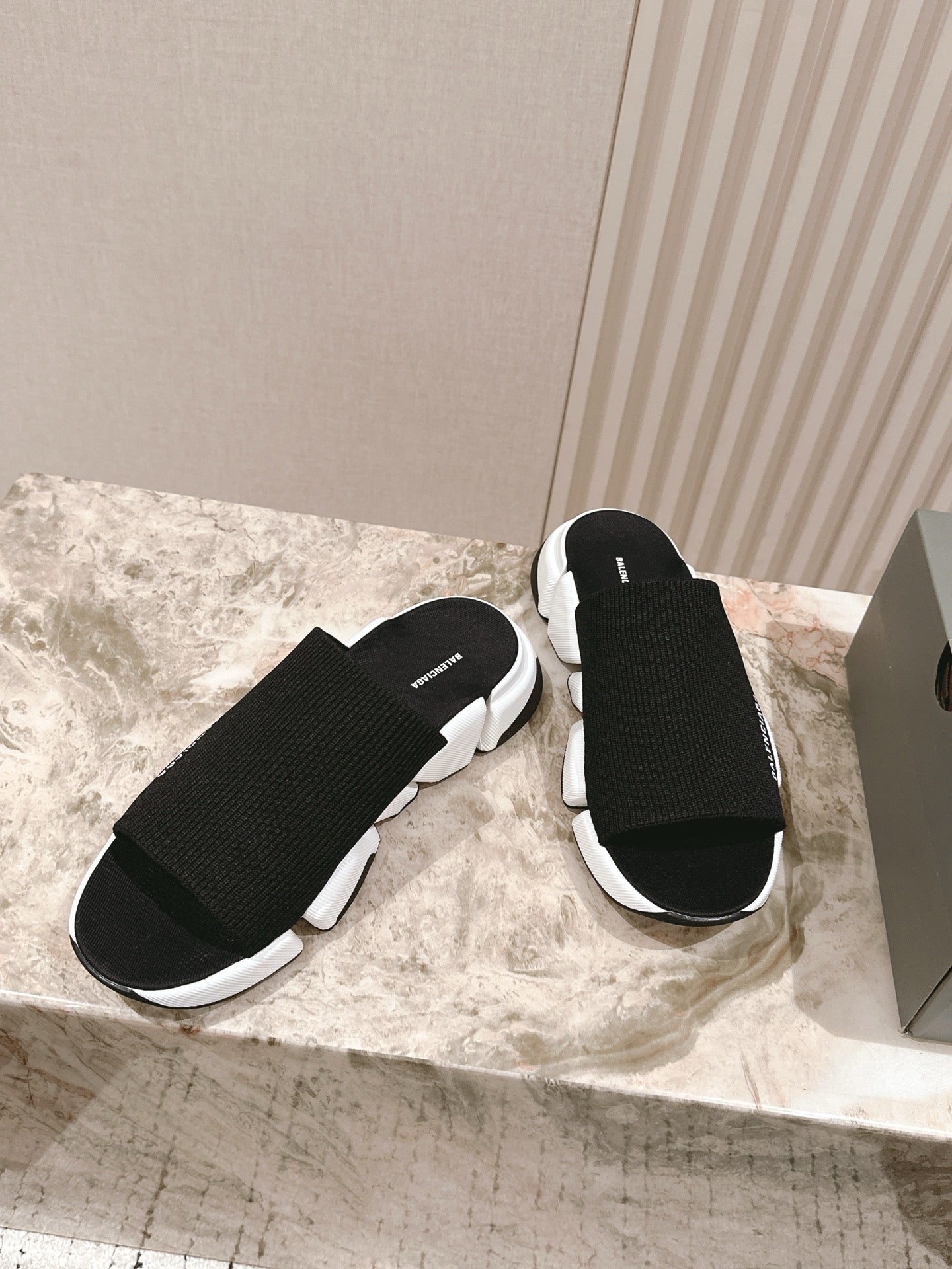 Black knit slide sandals with chunky white sole and Balenciaga logo strap.