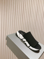 Black knit slide sandals with white sole and Balenciaga logo strap.