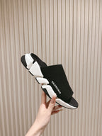 Black knit slide sandals with white midsole and Balenciaga logo strap.
