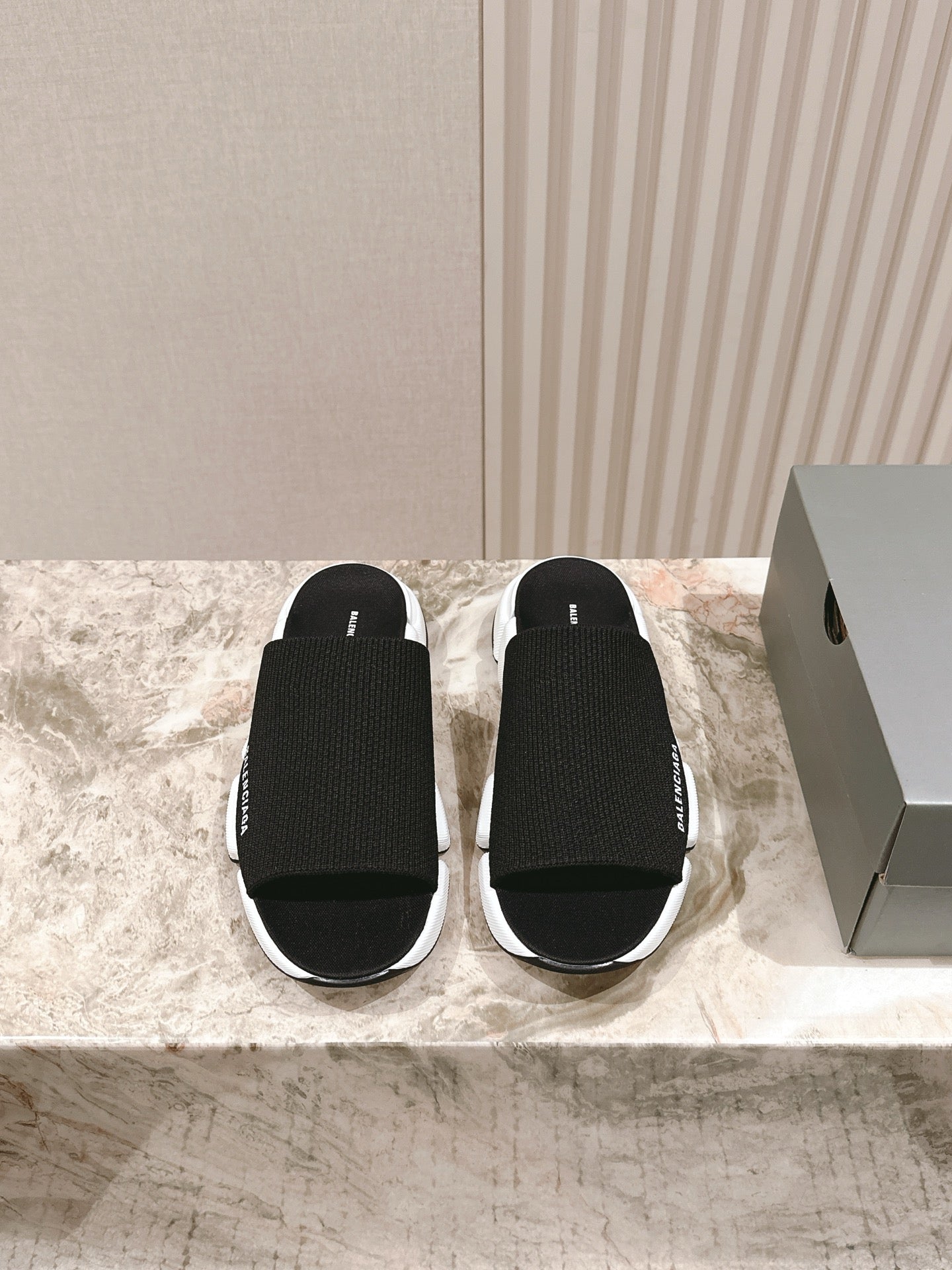 Black knit slide sandals with white sole, Balenciaga logo on strap.
