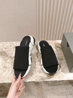 Black slide sandals with white sole and Balenciaga logo on the strap.