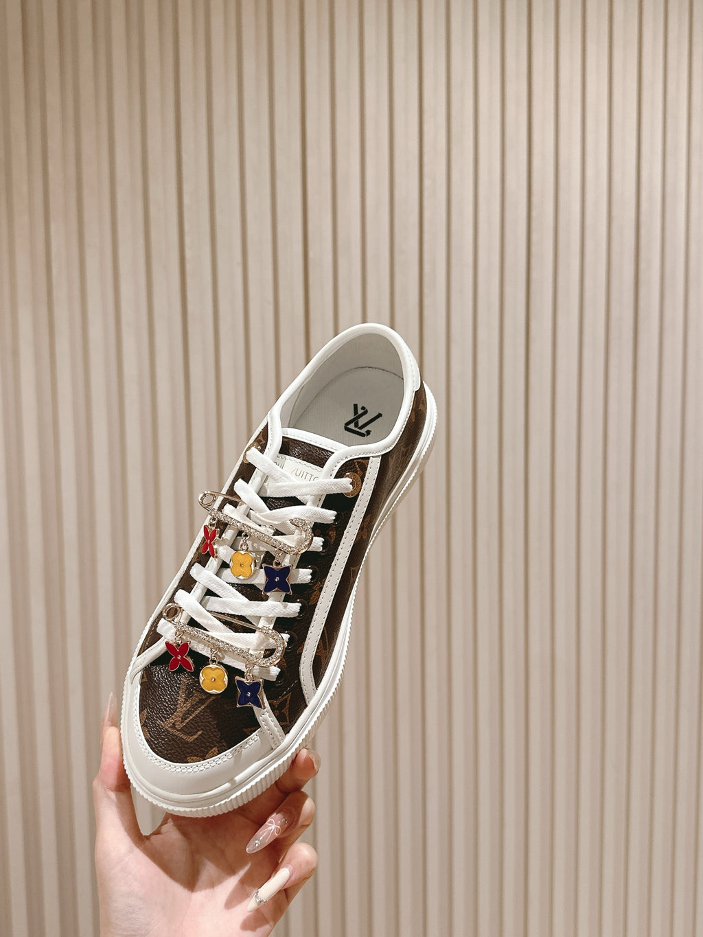 Louis Vuitton low-top sneaker, side profile with white laces and colorful charm details