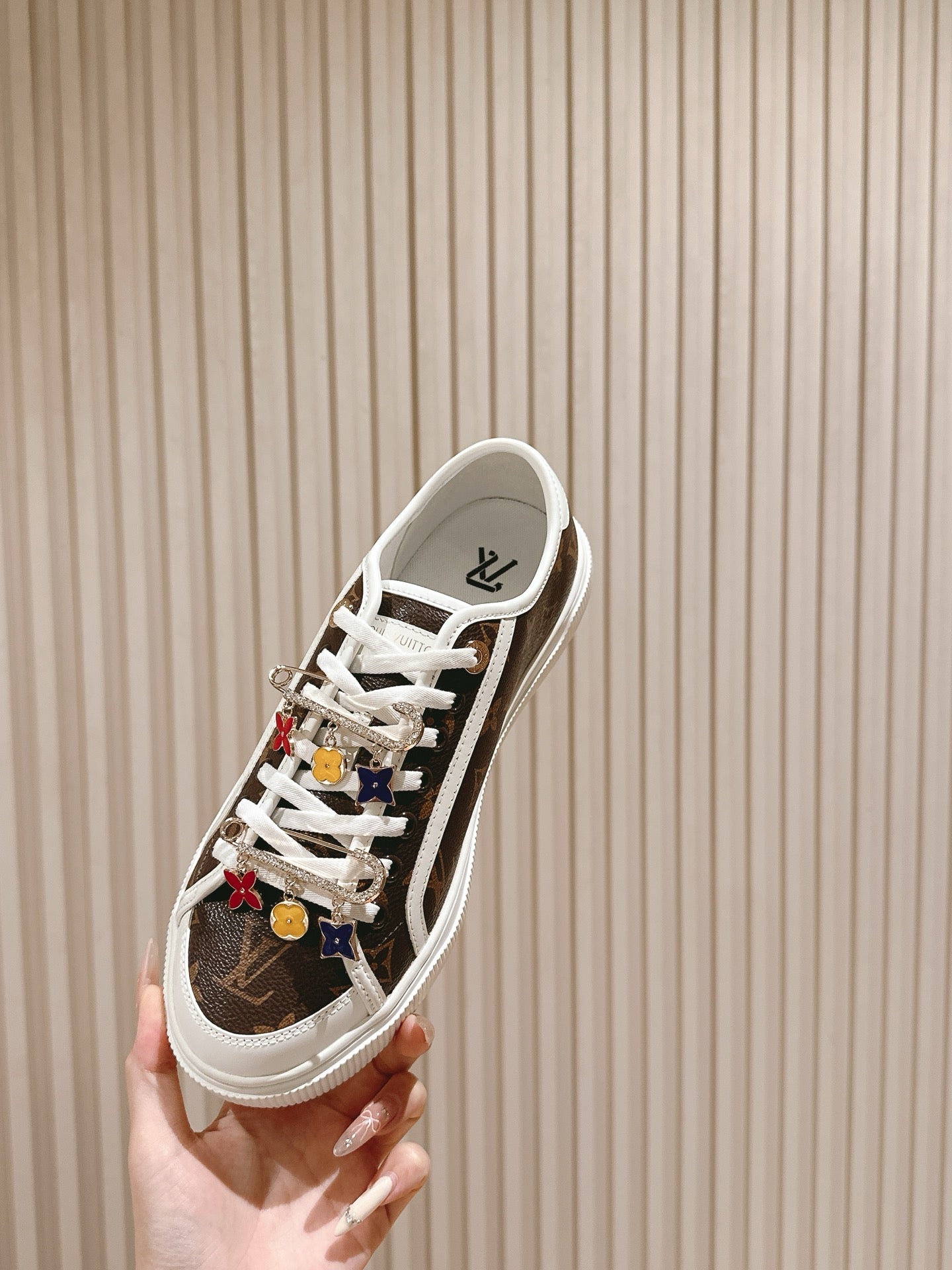 Louis Vuitton low-top sneaker, side profile with white laces and colorful charm details