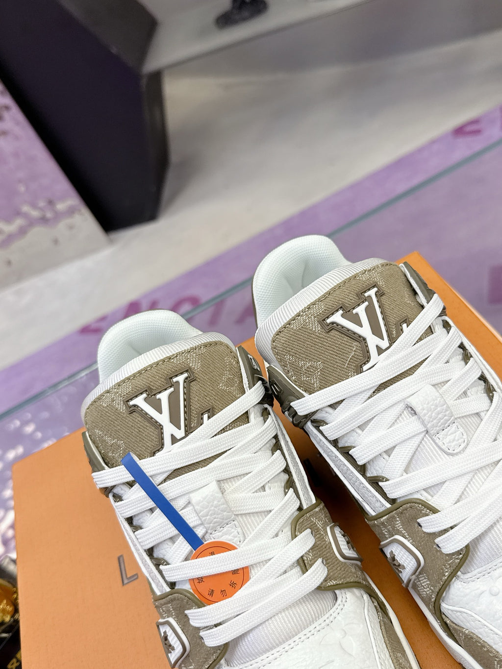 Women’s Louis Vuitton sneaker close-up, white and olive uppers with monogram detail