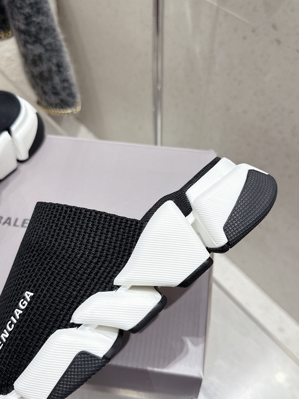 Balenciaga black slide sandals with knit strap and white chunky sole, angled close-up