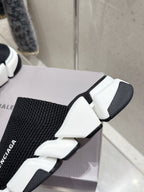 Balenciaga black slide sandals with knit strap and white chunky sole, angled close-up