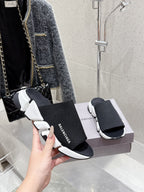 Balenciaga black slide sandals with knit strap and white sole, hand holding pair