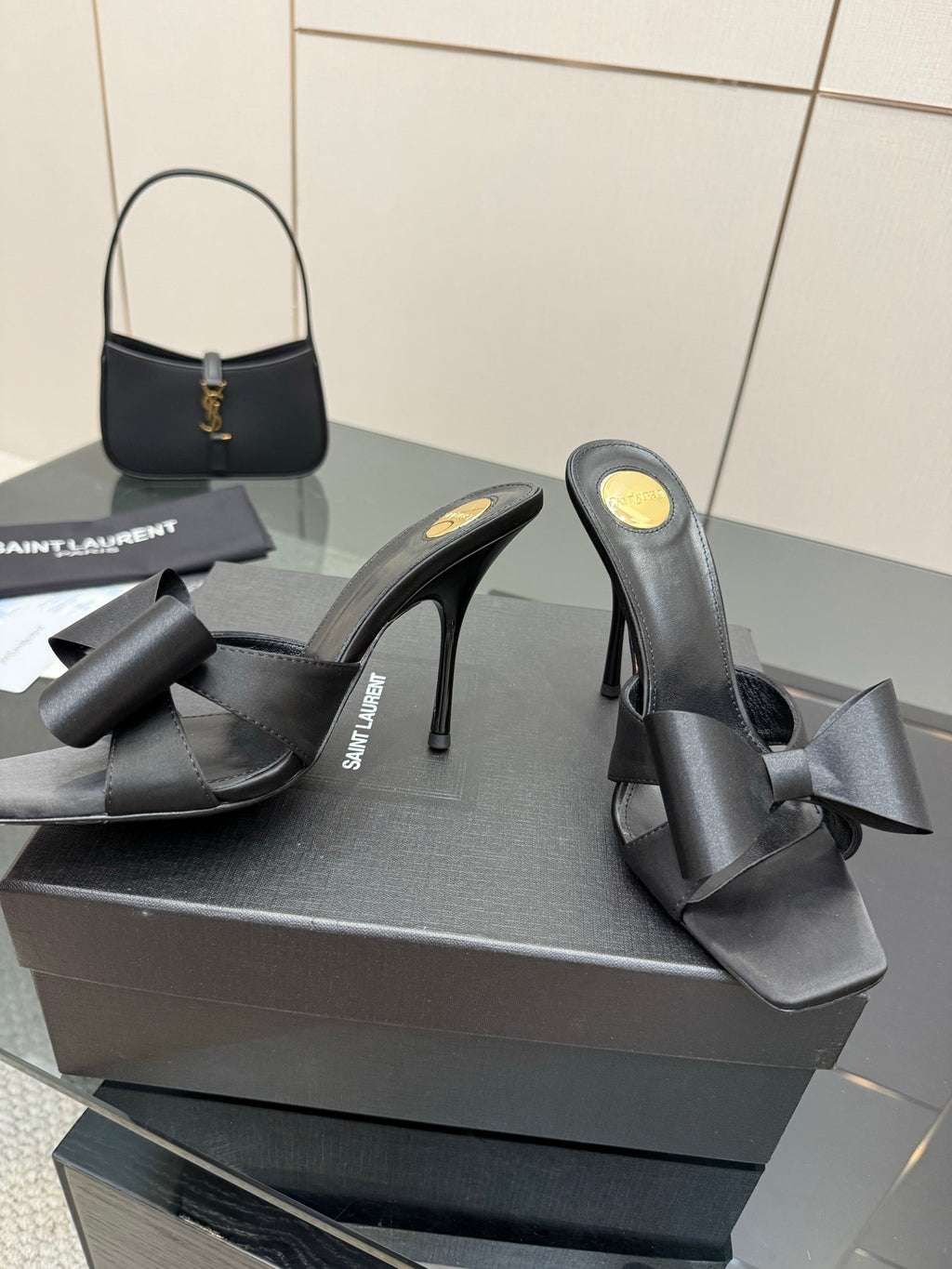 YSL black high-heel mule sandals with wide bow detail, angled view on display