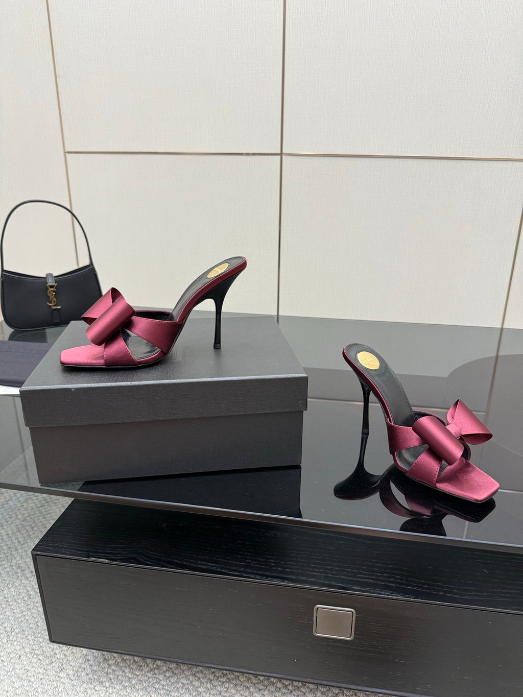 YSL pink satin bow mules with black high heel, angled on display box