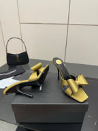 Yellow satin bow mules with black interior and tall stiletto heel