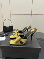 Yellow bow heeled mules with black footbed and high stiletto heels