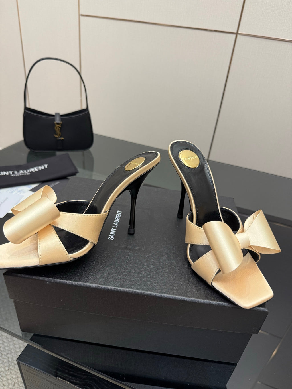 Two-tone heeled mules with beige bow detail and black lining, slender stiletto heel