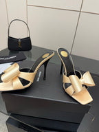 Two-tone heeled mules with beige bow detail and black lining, slender stiletto heel