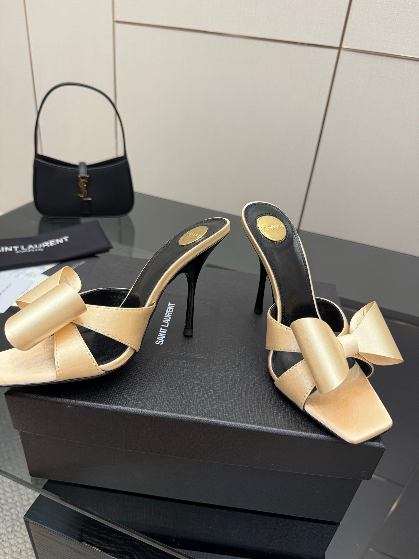 Two-tone heeled mules with beige bow detail and black lining, slender stiletto heel