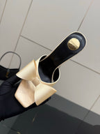 Back view of two-tone mule heel, beige bow on black upper with curved stiletto