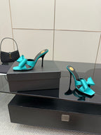 Turquoise bow mule heels on display box, pair with stiletto heels and open toe