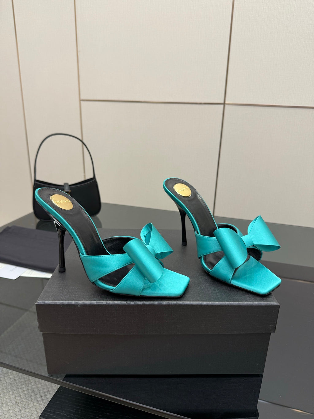 Turquoise bow mule heels on display box, black footbed, slender stiletto heel