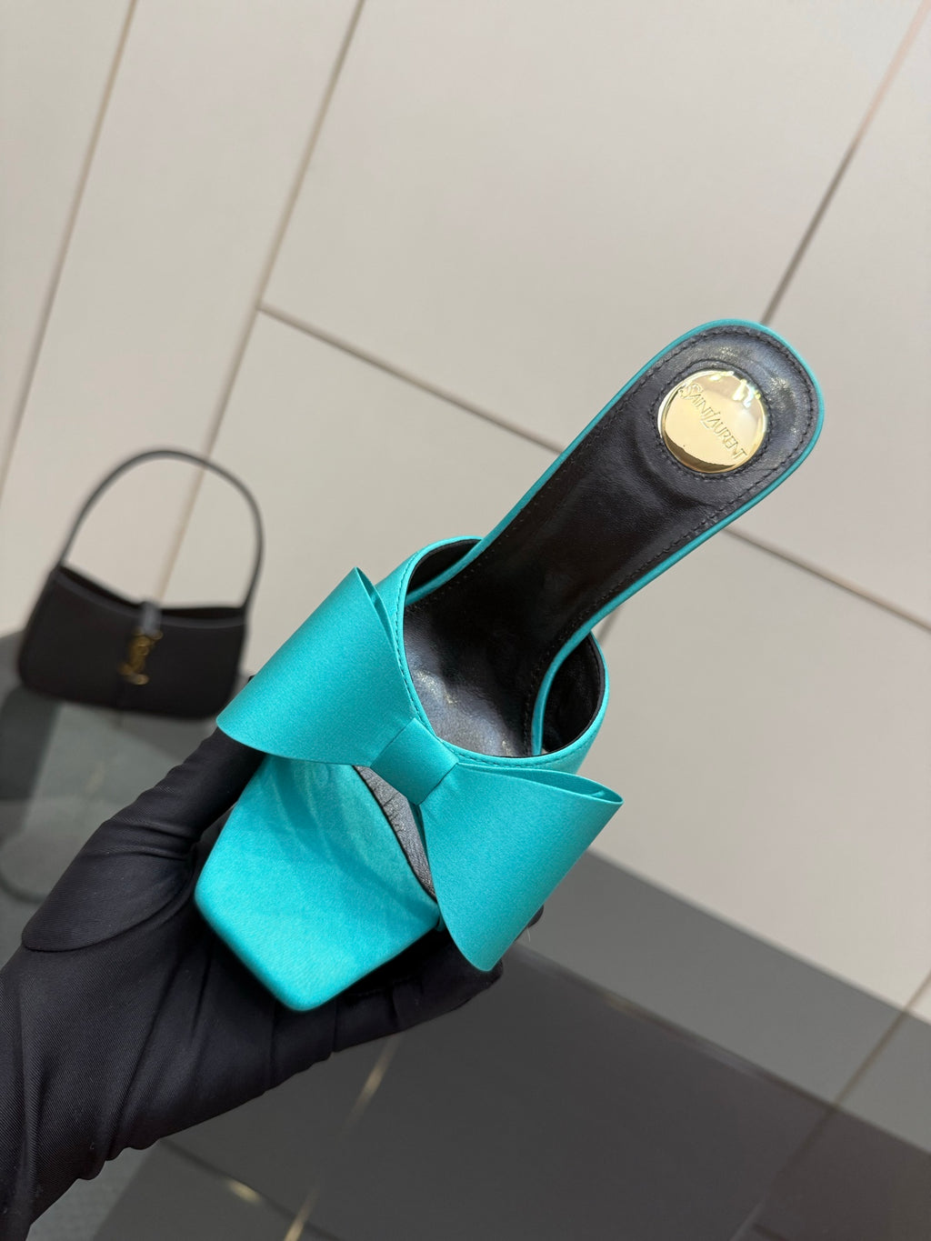 Turquoise bow mule heel close-up in hand, black interior visible