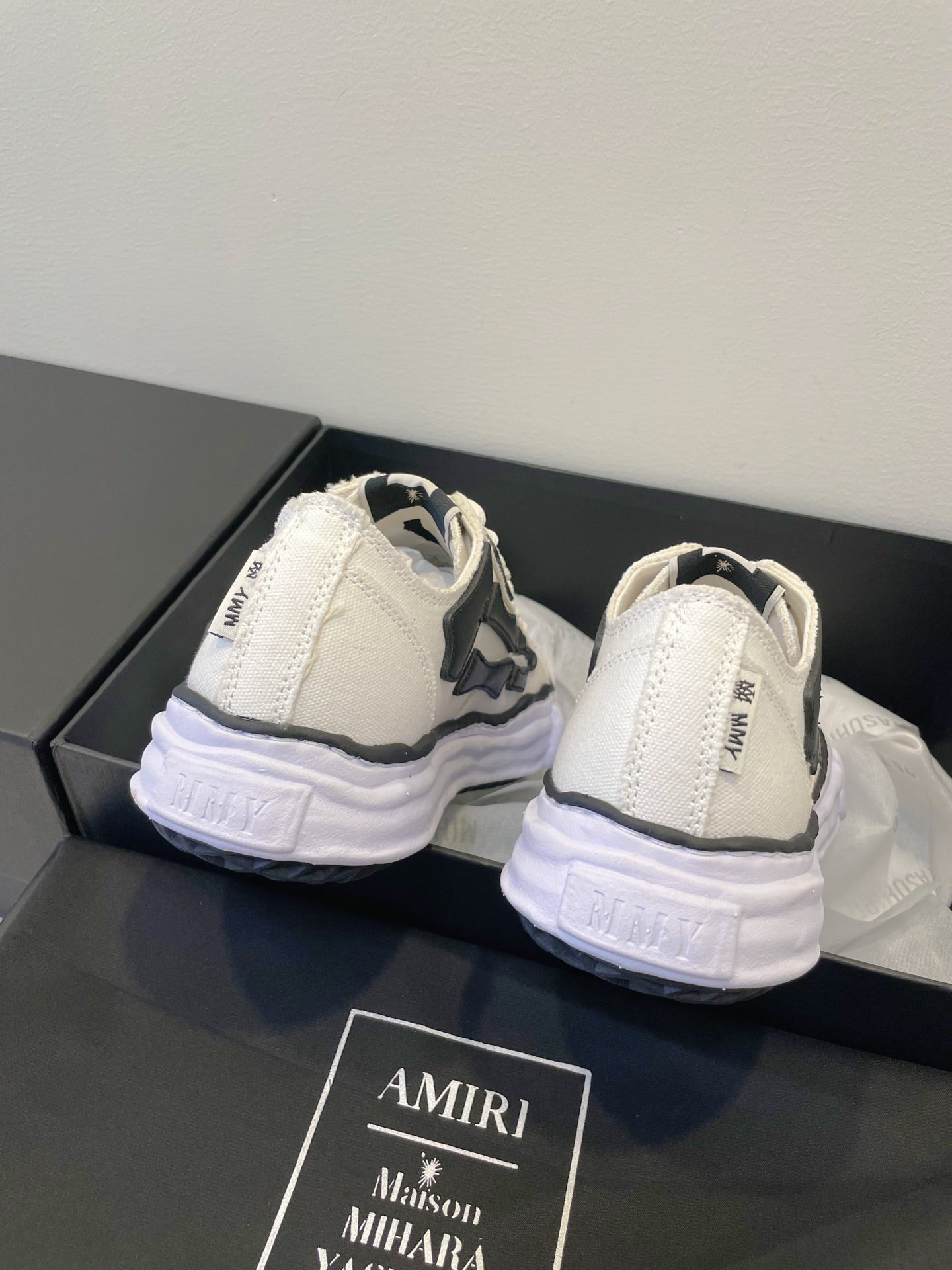 Amiri white and black lace-up sneakers, heel and back view on display