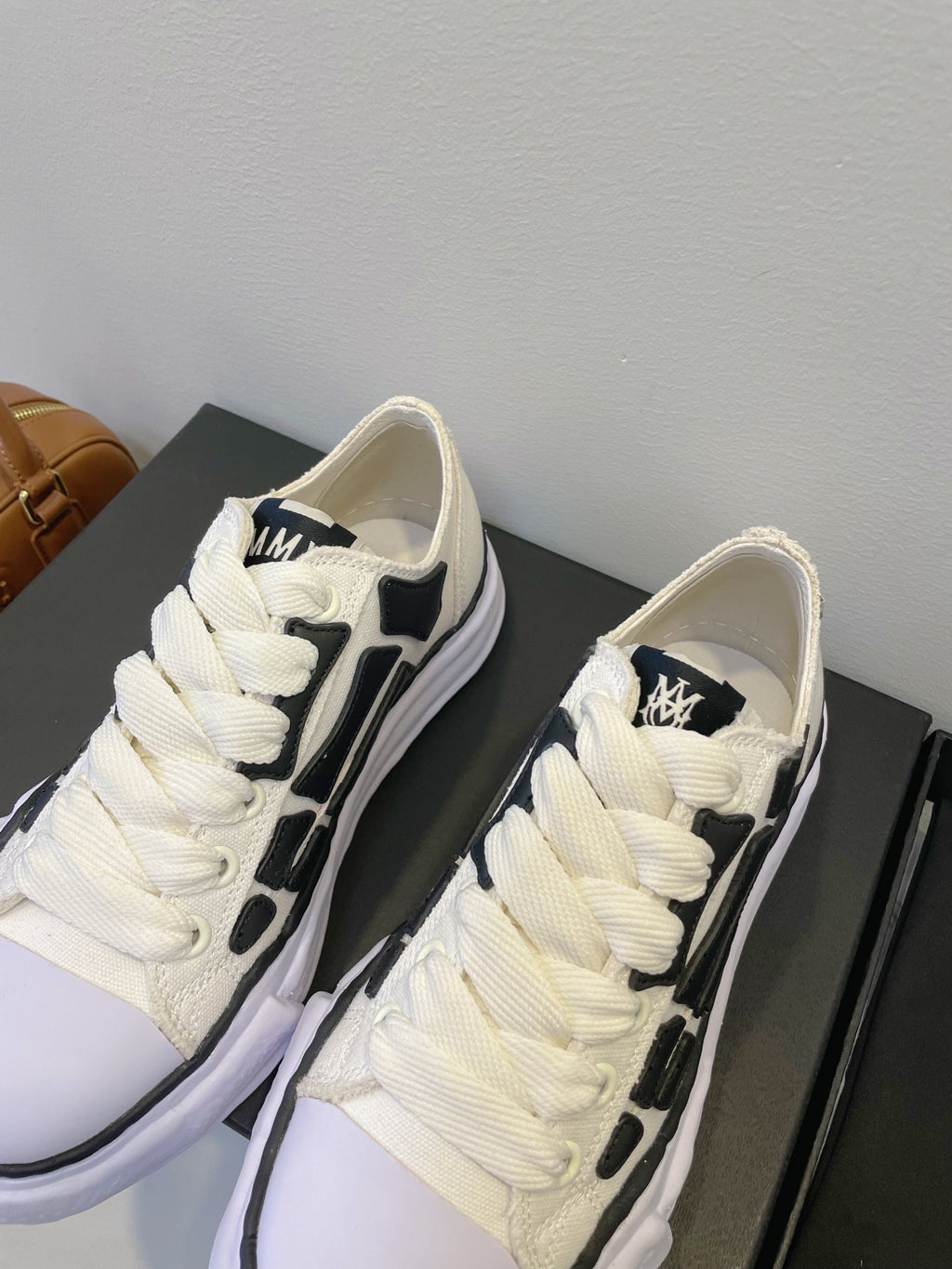 Amiri white lace-up sneakers with black logo panel, front close-up