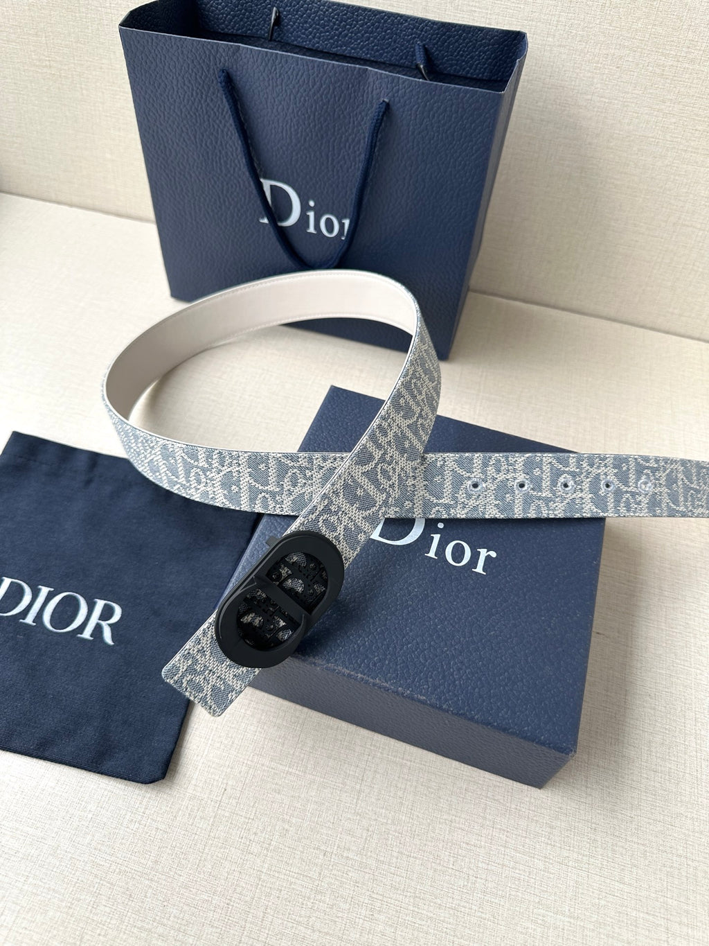 Dior belt with patterned strap, black oval buckle, and white belt keeper