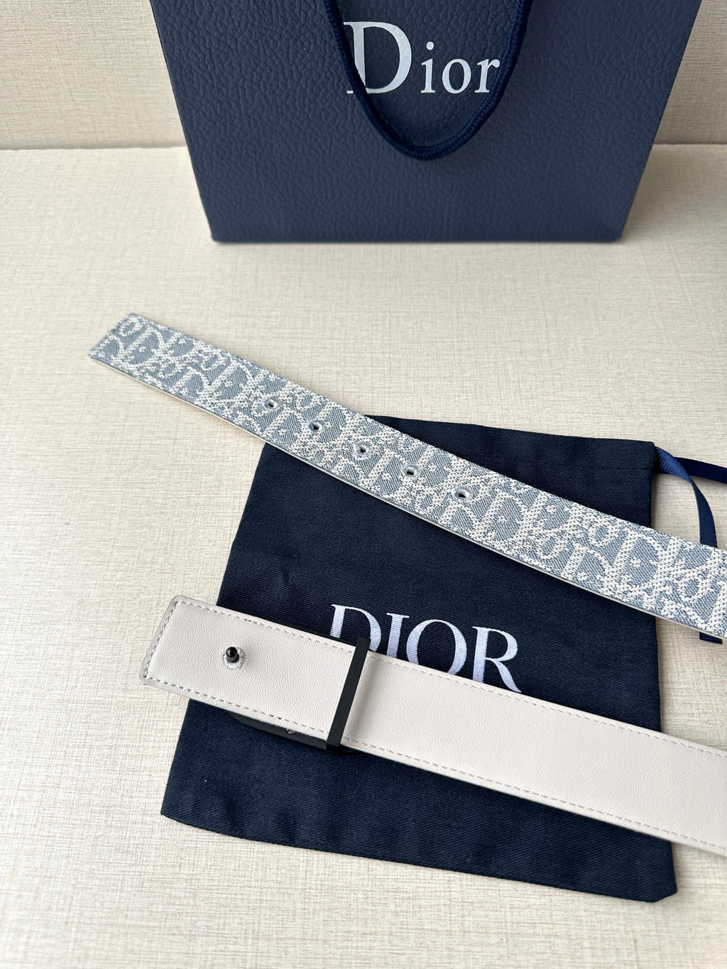 Dior belt with patterned strap, black oval buckle, and white buckle keeper
