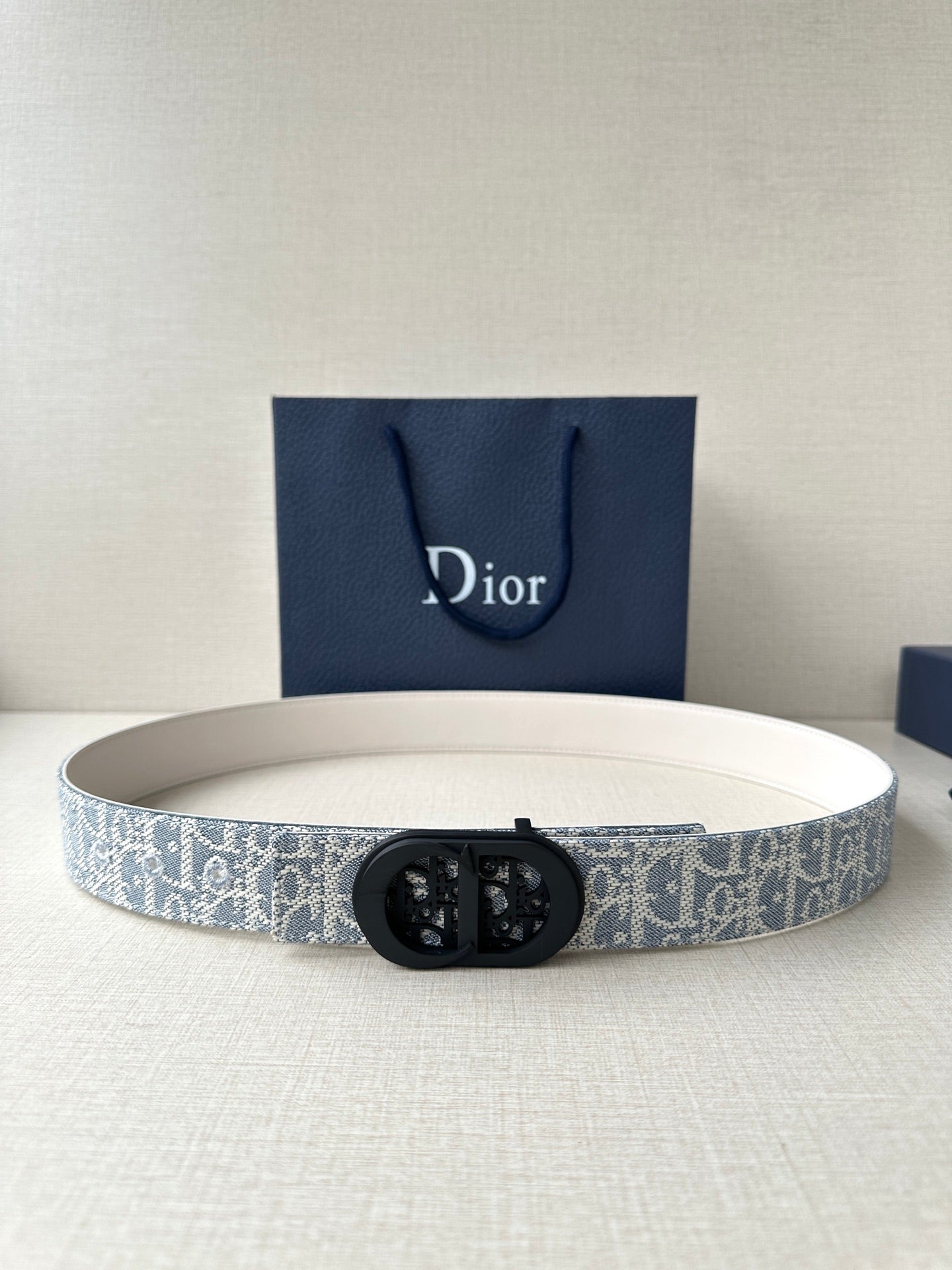 Dior belt with light blue patterned strap and black oval logo buckle