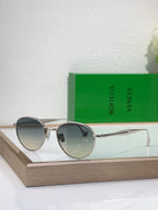 Bottega Veneta round sunglasses with gold-tone metal frame and blue-gray tinted lenses