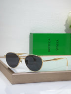 Bottega Veneta round sunglasses with gold-tone metal frame and dark charcoal tinted lenses