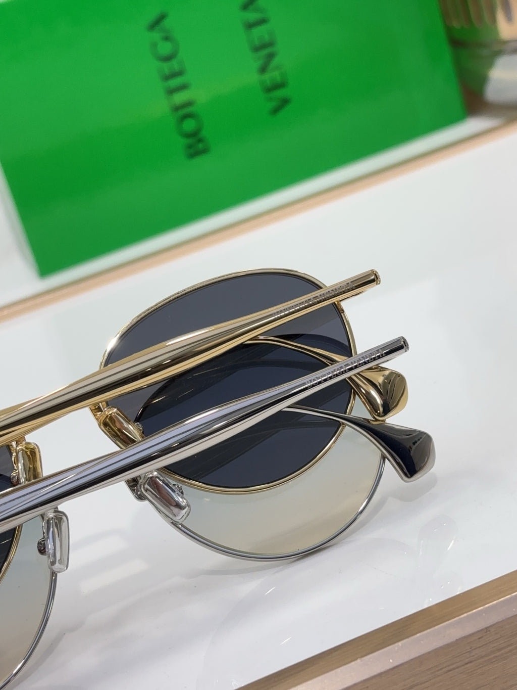 Bottega Veneta round sunglasses close-up, gold-tone frame with dark blue mirrored lenses